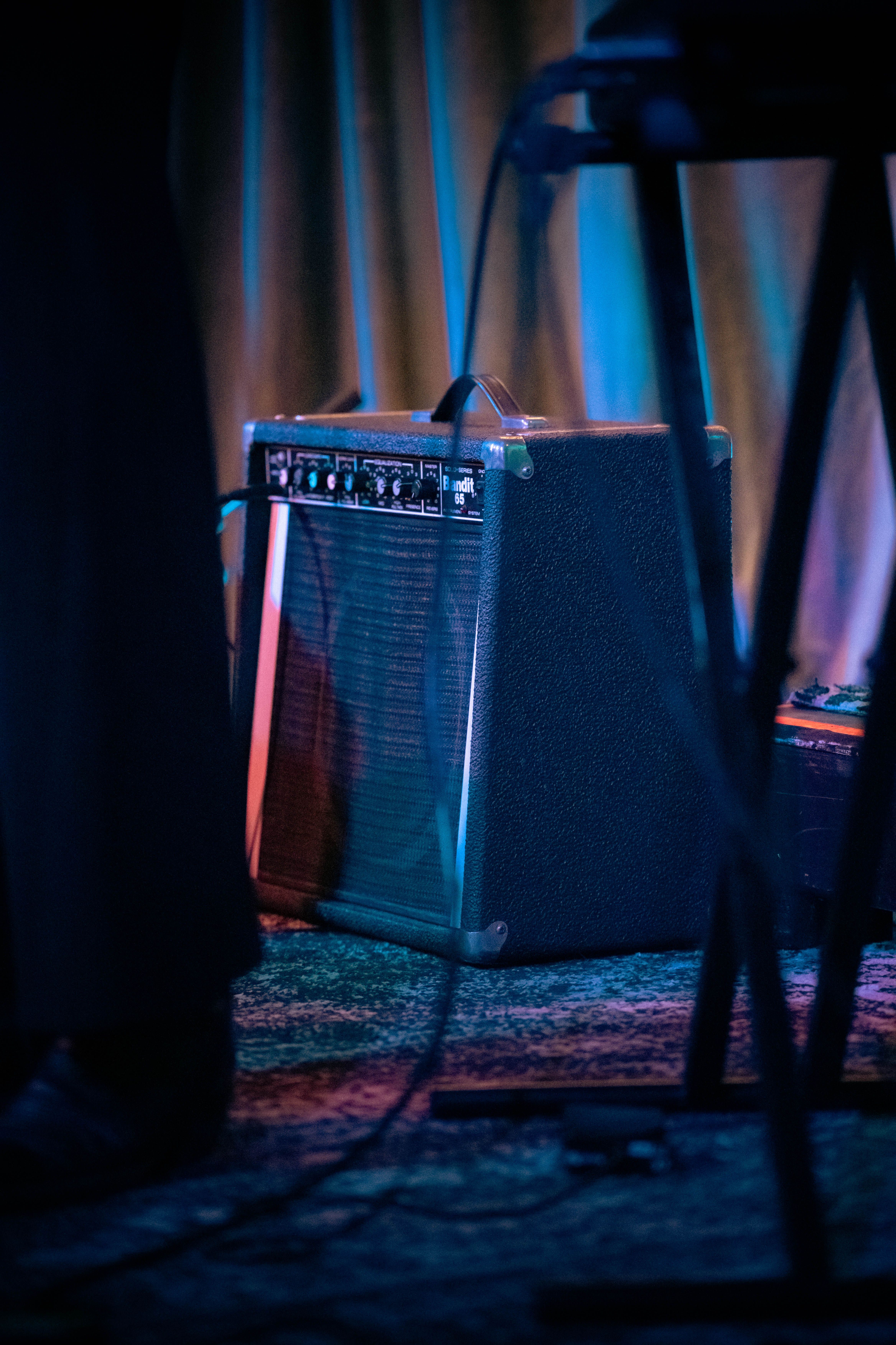 A guitar combo amplifier illuminated under stage lighting at a live venue.
